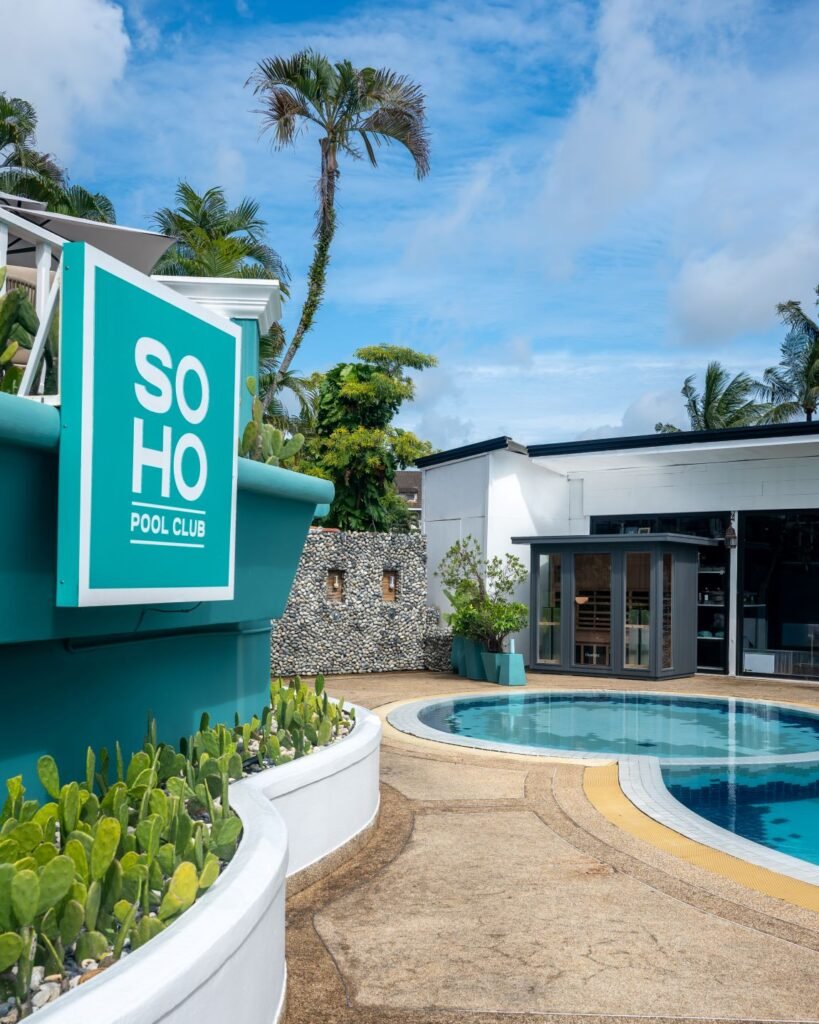 SOHO Wellness infrared sauna by the pool at SOHO Pool Club Phuket surrounded by tropical palm trees and bright blue skies.